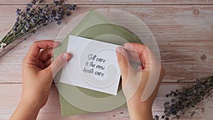 SELF CARE IS THE NEW HEALTH CARE text on supportive message paper note reminder from green envelope. Flat lay