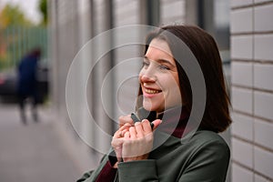 Self-confidence. A pleasant youthful girl standing next to a new white car and smiling