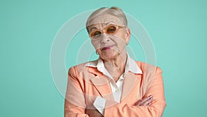 Self confident blonde senior woman in stylish glasses crossing hands on chest