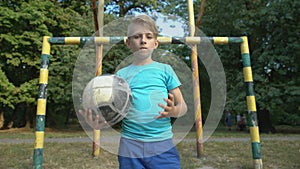 Self-confident boy footballer with ball looking at camera, welcoming for match