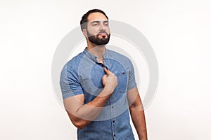 Self confident egoistic man with beard in blue shirt pointing finger at chest showing his strength and importance, proud of