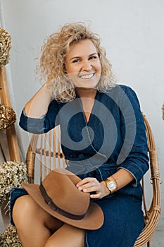 Self-confident, happy, self-sufficient woman of 40 with fluffy blond hair, sitting and looking into frame, smiling and laughing.