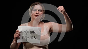 Self confident plus size Caucasian woman looking at camera raising Woman power poster gesturing strength gesture