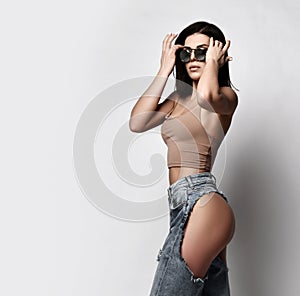 Self-confident sexy adult woman is walking in torn jeans with naked butt, ass, sunglasses and top. Side view