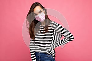 Self-confident shot of young charming brunette woman wearing mediacal face mask isolated over pink background wall