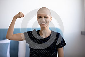 Self confident woman combating against oncology demonstrate muscles strength symbol