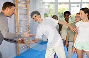 Self-defence course instructor demonstrating painful wristlock to teenagers
