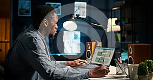 Self employed Black man multitasking at home taking handwritten notes