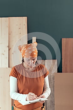 Self employed female carpenter writing project notes