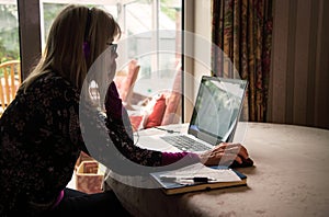 Self employed woman listening to webinar on her laptop,wearing headphones photo