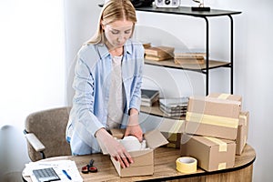 self employed woman packing product in cardboard box