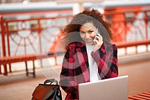 Self employed woman working with her phone and laptop in a restaurant terrace