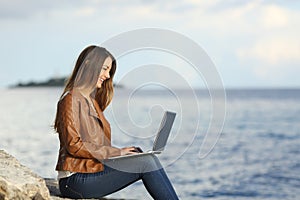 Self employed woman working with a laptop on the beach