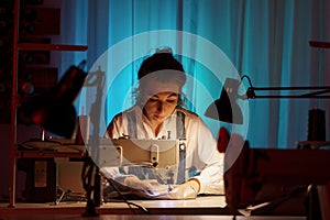 Self-employed young woman work on sewing machine in little creative atelier creating bespoke clothes