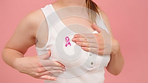 Self examination of the breasts, breast cancer awareness concept. Isolated on pink background