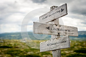 self-isolation lockdown quarantine text engraved on old wooden signpost outdoors in nature photo