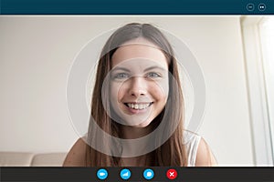 Young woman looks at webcam communicating with boyfriend by videocall photo