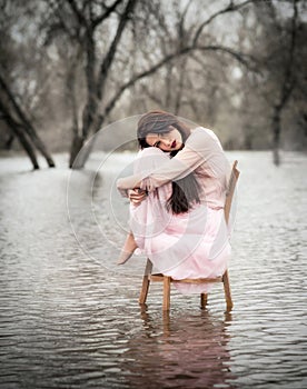 Self-isolation in quarantine. The girl sits on a chair in the water. Pandemic, flood