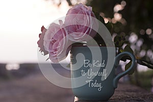 Self love and care inspirational quote on coffee cup - Be kind to  yourself today. With pink roses and coffee cup vase decoration.