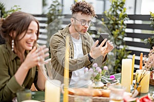 Self lover guy looking at himself on phone while dining with friends outdoors