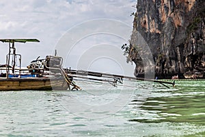 The self-made engine from the pickup truck is mounted on a long-tailed motor boat against the background of a sandy beach with