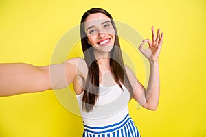 Self-portrait of attractive cheerful girl showing ok-ad advert deal done isolated over vibrant yellow color background
