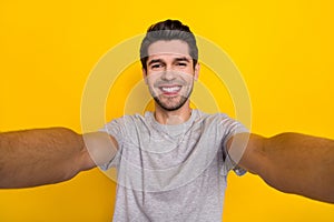Self-portrait of attractive cheerful guy wearing tsirt good mood isolated over bright yellow color background