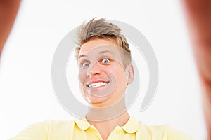 Self-portrait of attractive handsome wild manly guy in casual yellow polo t shirt, smile white teeth, isolated over bright white