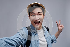 Self portrait of cheerfu blogger showing peace symbol with two fingers to the camera, making video for his blog