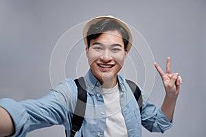 Self portrait of cheerfu blogger showing peace symbol with two fingers to the camera, making video for his blog