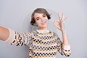 Self-portrait of lovely cheerful girl showing ok-sign deal ad cool isolated over grey pastel color background