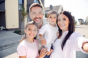 Self-portrait of nice cheerful lovely family embracing mom dad carrying son spending time fresh air in cottage town