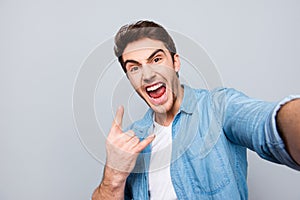 Self portrait of shouting, foolish, individual, attractive, crazy, funny man with wide open mouth, stubble in jeans shirt