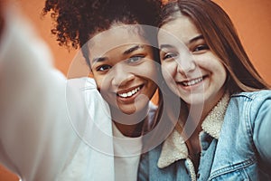 Self-portrait of two happy joyful teen girls of different races making selfie, enjoying friendship