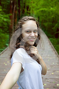 Self portrait of young smiling smiling woman on nature in forest or summer park. Travel. Selfie