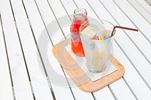 Self pouring ice tea serve with ice cube with fruits frozen inside on a wooden plate and table