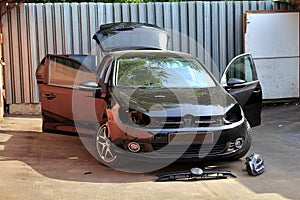 Self repair of a car at summer, near garage. Changing headlights. Black hatcback without front headlights and grill of radiator photo