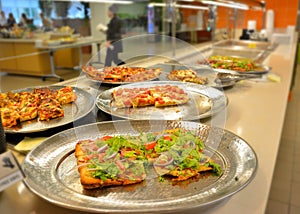Self serve pizza at a cafeteria with diners and waiter