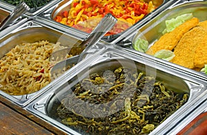 Self service canteen with breaded meat cutlet and cooked spinach photo