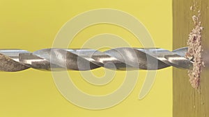 A self-tapping screw in a wooden block on a yellow background. Screwdriver screw lag bolt. Vertical video