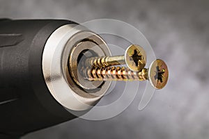 Self-tapping screws are inserted into the power tool with the reverse side. Concept on the misuse of a screwdriver photo