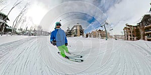 SELFIE: Active man skis along a groomed slope running between ski resort lodges