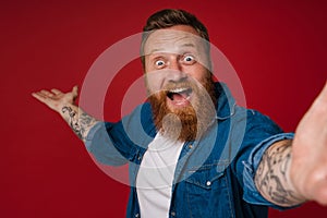 Selfie of adult bearded tattooed handsome enthusiastic redhead man