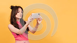 Selfie, A beautiful girl taking pictures of herself on her phone. On a yellow background. instagram