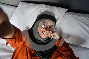 Selfie of beautiful smiling woman in hijab and glasses