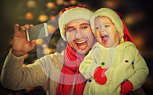 Selfie in Christmas. happy family dad playing with daughter and photographed on mobile phone