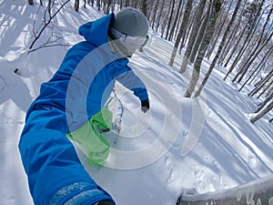 SELFIE Cool freeride snowboarder carving powder snow between the dangerous trees