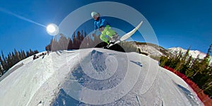 SELFIE: Extreme snowboarder jumps high in the air off a kicker in snow park.