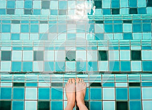 Selfie of feet and legs in green swimming pool and waves background or texture. Top view. Beautiful young female barefoot under