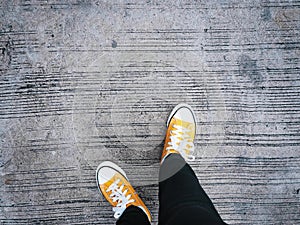 Selfie feet wearing yellow sneakers on concrete road